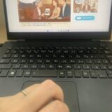 『真心マッチ』運営責任者「ぱんこす」（カタオカコウジ）の執筆風景。左手薬指に指輪をした既婚の管理人が、ノートパソコンで公式サイトを確認しながら記事を作成している手元の様子。（実写）